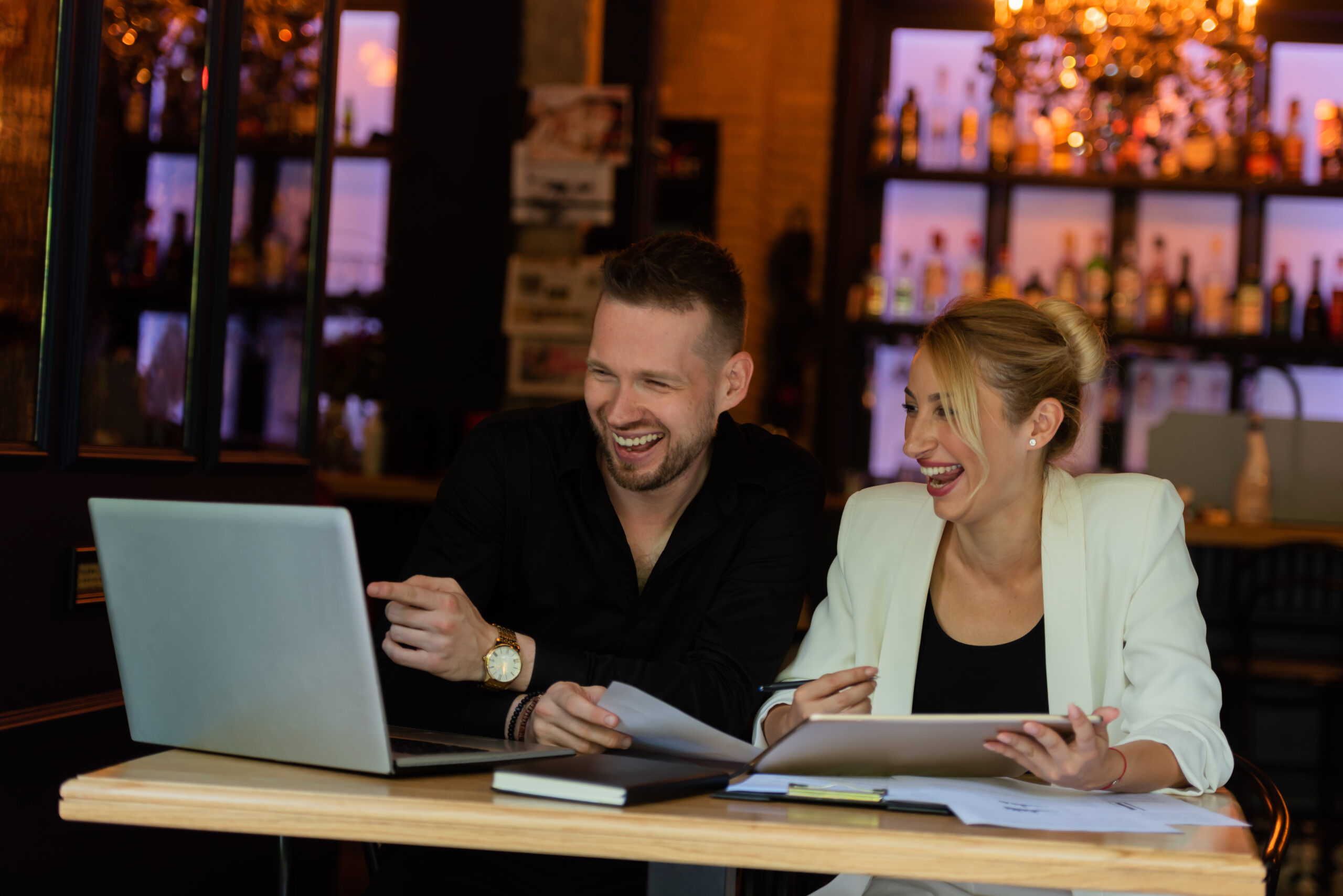Shot of a young businesswoman and businessman using a digital tablet and laptop while having a discussion in a cafe